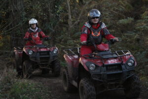 A close-up of two people sat on quad bikes.